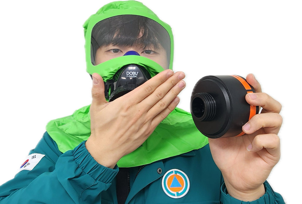 초록색 덮게 방독면을 손으로 입을 가리고 정화통을 해체한 사진